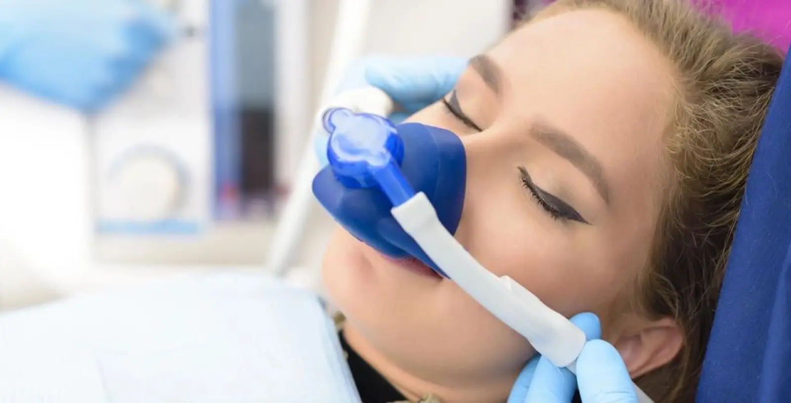 a woman is laying in a dental chair with an oxygen mask on her face .