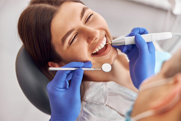 a woman is sitting in a dental chair looking at her teeth in a mirror .